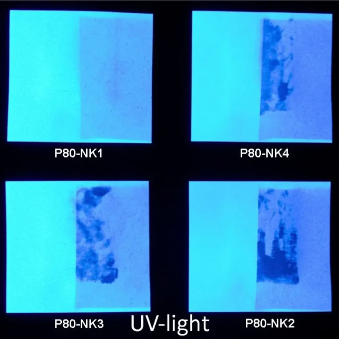 the same four paper samples from the previous image under UV radiation. the papers are bright white-blue in places, with dark spots in places.