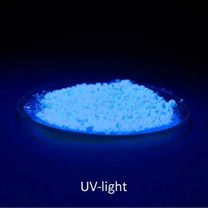 In the centre is a glass bowl with a white-blue glowing powder against a black background. It shows the fluorescence of optical brighteners under ultraviolet radiation