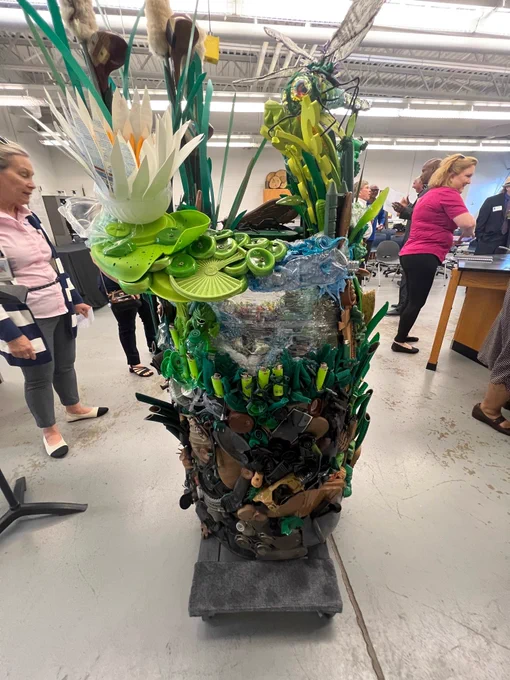 A photo of a large sculpture featuring a dragonfly made with found items