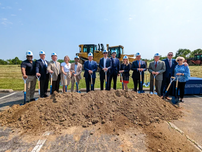 College officials pose in front of a pile of dirt at the groundbreaking ceremony, all hold shovels.