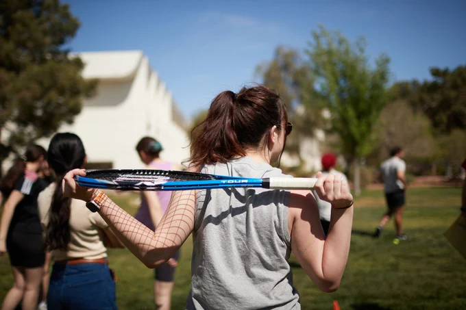 A student holds a tennis racket behind her back