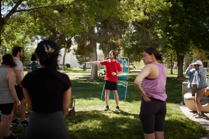 A professor gestures in front of a small goal during a class held outdoors