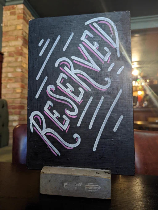 A tabletop blackboard sign in The Actors that says RESERVED in fancy lettering.
