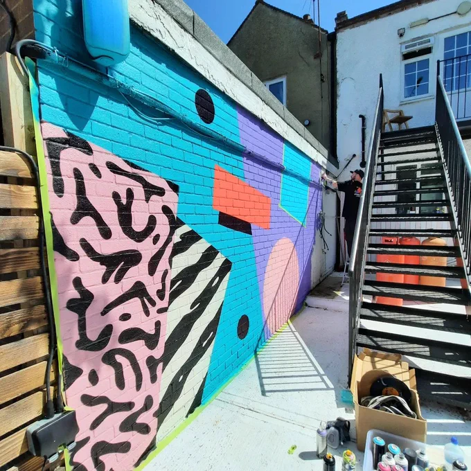 Street art created on a wall in the outside space of foureighty in Shenfield.  Artist:  Mr Penfold.

Modern artwork, pink, black, blue, white, orange patterns