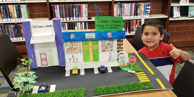 A child posing with his model of Graham Library