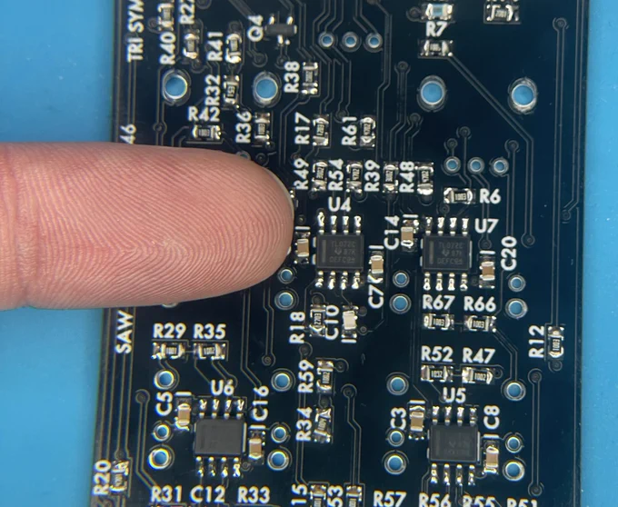 A circuit board covered with tiny electronic components, with an index finger for scale?