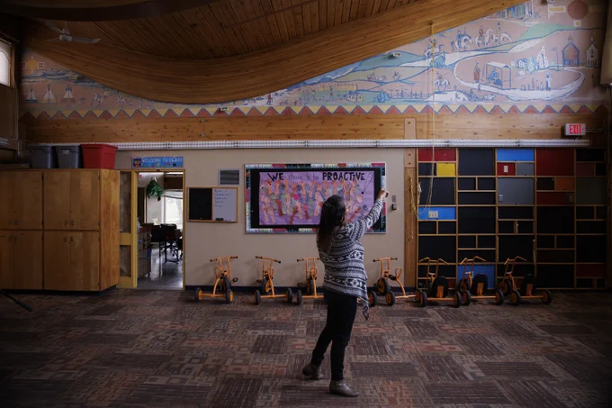Tara Cutarm points out the details of a mural depicting first contact, at Ermineskin Kindergarten Community School, on Ermineskin 138 reserve in Maskwacis, Alberta, June 7, 2022.