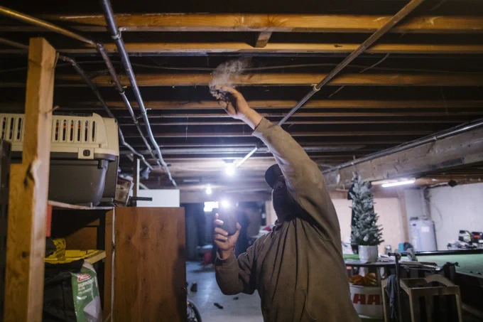 Karl Meier swipes a pile of silt left behind by the flood from wooden beams in his basement in Abbotsford, British Columbia on Tuesday, September 27, 2022. 
