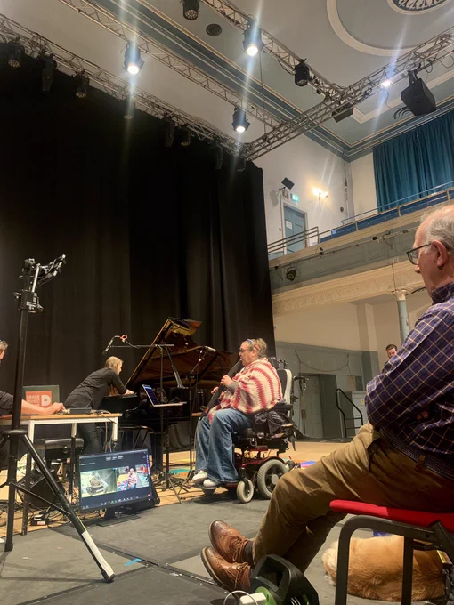 Two musicians experiment on piano and electronic wind instrument in a concert hall