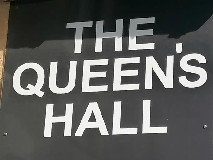 Sign saying THE QUEEN'S HALL in bold white against a black background