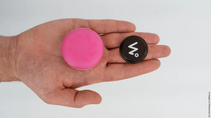 Image: A round, red button and a round, black sensor with a white M on the palm of a hand; Copyright: Knopka LLC / Movesense Ltd.