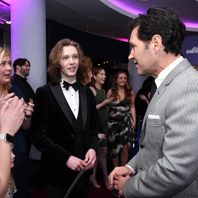 George meeting Paul Rudd on the red carpet. Paul is in a grey suit and George is wearing a bow tie and a suit. 