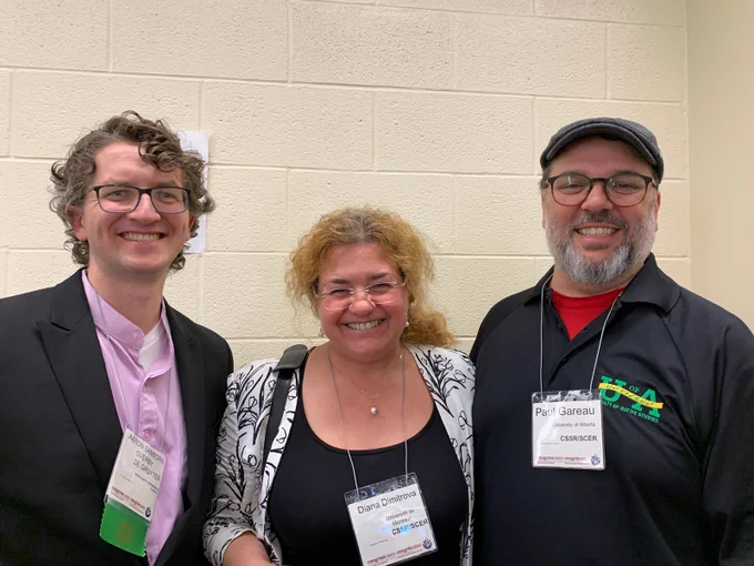 Photo of Aaron Sanborn-Overby, Diana Dimitrova, and Paul Gareau; background cream painted cinderblock wall.