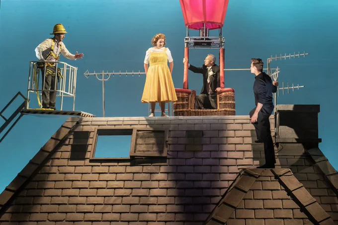 A photo showing four cast members standing on a roof on stage