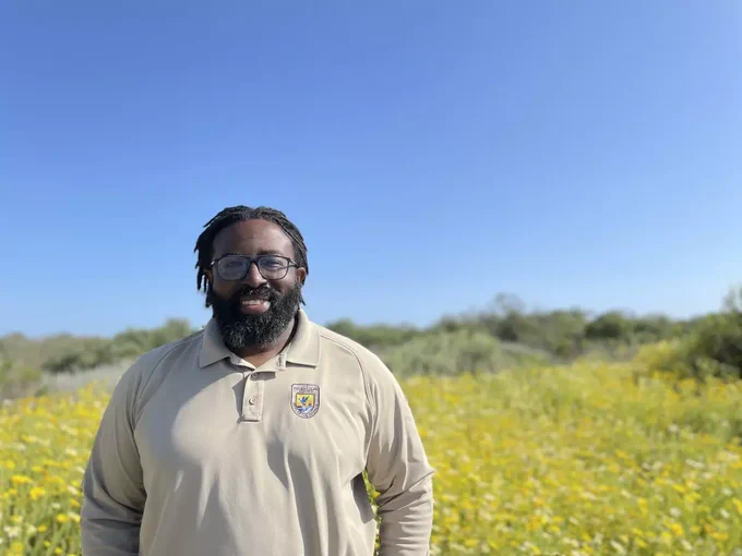 Nick standing outdoors with a flower field behind him