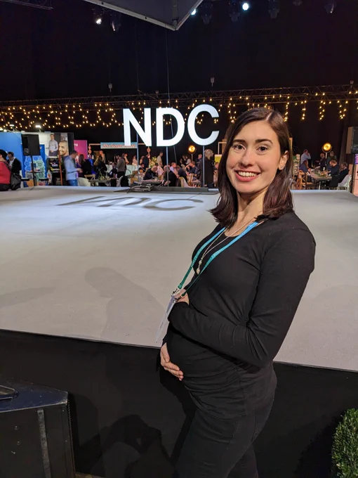 Melissa in front of an NDC sign holding her pregnant belly 