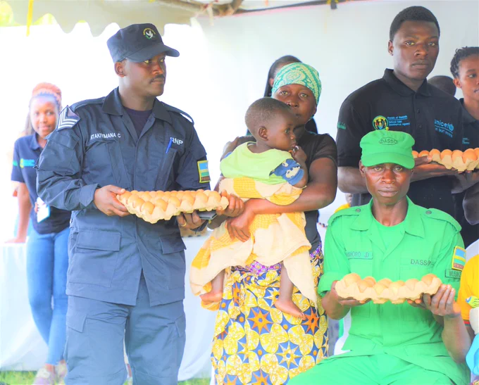 Security officials participate in the handing out of crates of eggs to mothers of young children.