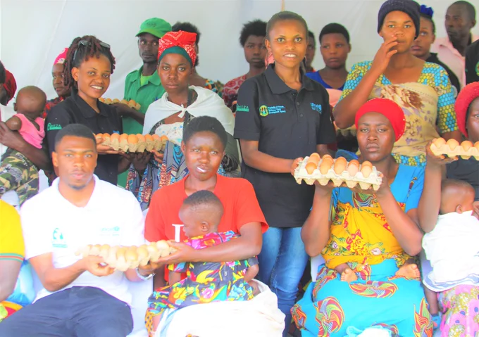 Volunteers and partners hand out egg crates to mothers.