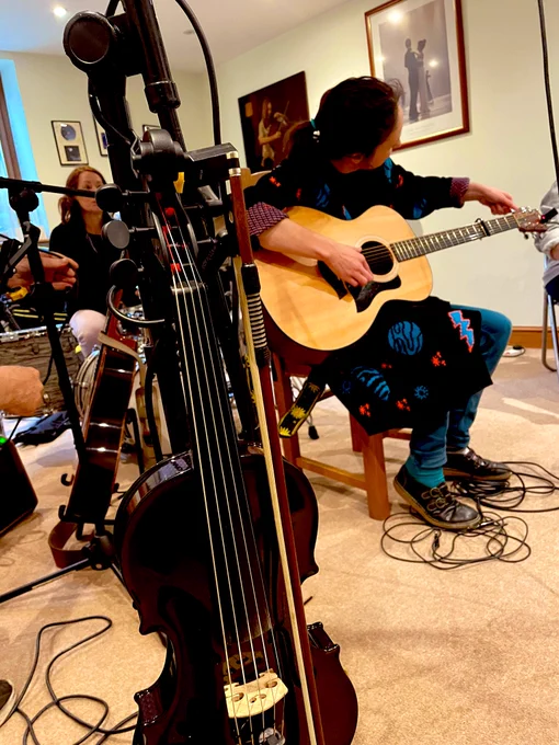 5 stringed violin in foreground, Gillian McCoy tuning guitar
