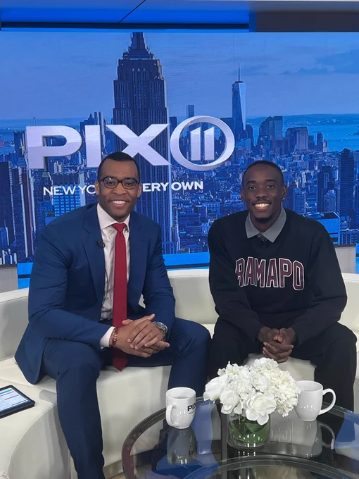 Justin Walters, an anchor for Pix 11 News, sits down on a couch in a news film studio with Ramapo College's track star, Cheickna Traore '23 for an interview. They are both facing us and smiling for the camera.