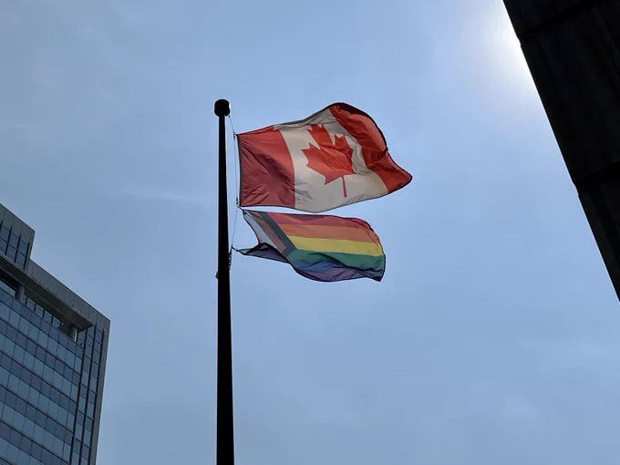 A photo of the Canadian Flag and the Progress Pride flag.