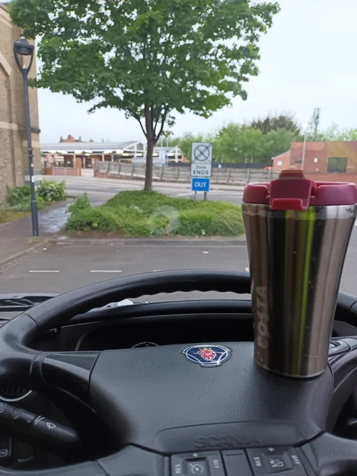 View out of coach window towards Goole Station, a Costa cup rests on the steering wheel.