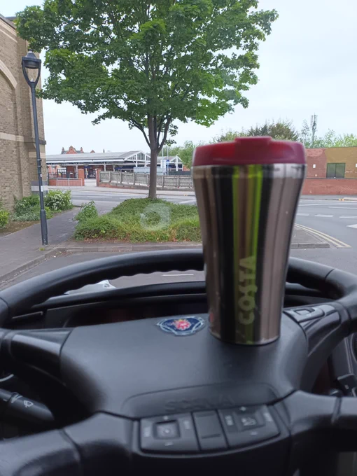 View out of coach window towards Goole Station, a Costa cup rests on the steering wheel.