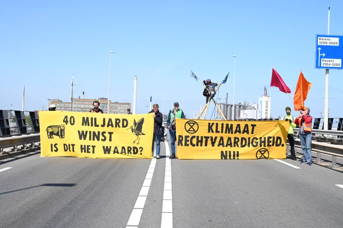 Actievoerders blokkeren de toegang tot Shell Pernis met spandoeken en een tripod.