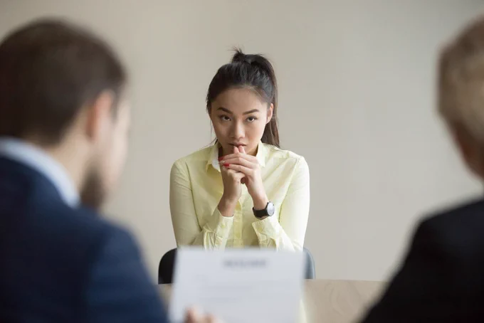 Young woman looking nervous being interviewed by 2 people