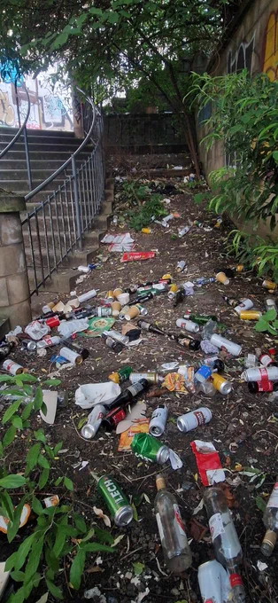 Many glass bottles and drinks cans littered over a small piece of ground on Holyrood Road