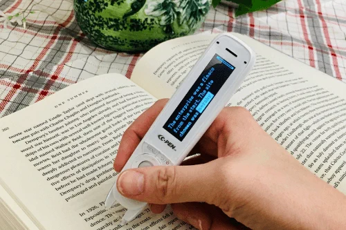 a hand holding a C-PEN ReaderPen over a book page