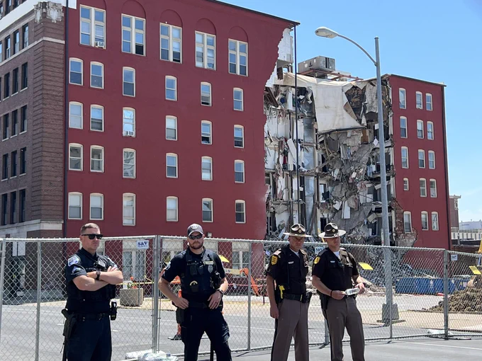 4 cops stand in front of a fence barricade outside of The Davenport, which partially collapsed on Sunday May 28.