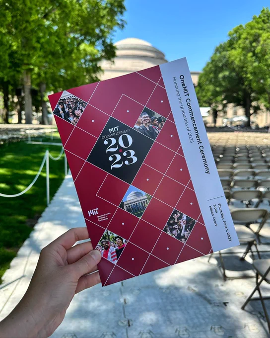 A hand holding up the program for Commencement 2023.