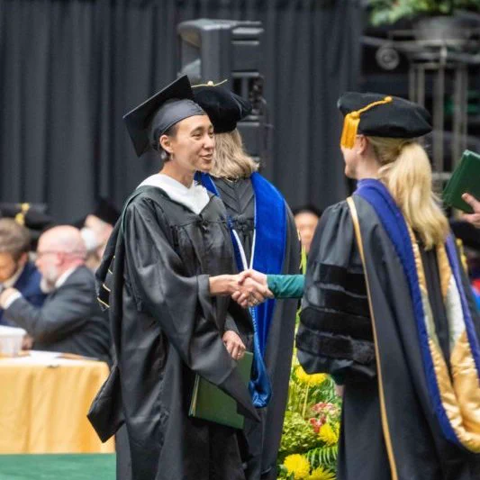Campell shakes President Amy Parsons hand as she recieves her degree.