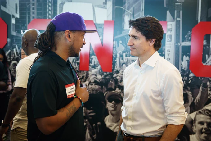 Prime Minister Justin Trudeau is standing and speaking with a man.