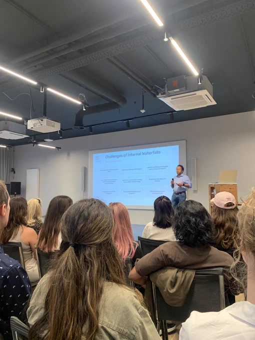 A person presenting a slide with a list of ‘Challenges of Internal Waterfall’