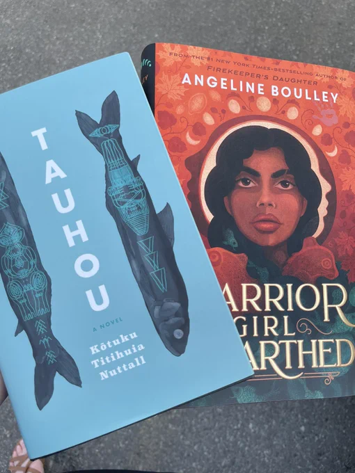 Two hardcover books. One is blue with two fish called Tauhou and one is called Warrior Girl Unearthed and is red.