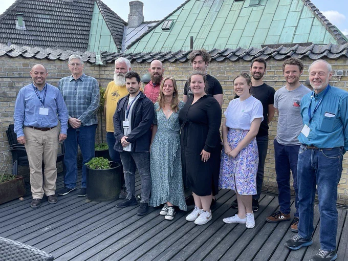 Group portrait of training course participants on a roof terrace with rooftops in the background.