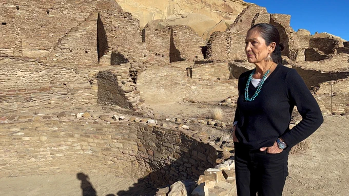 Secretary Haaland stands in front of living landscape of stone structures at Chaco Canyon National Historical Park. 
