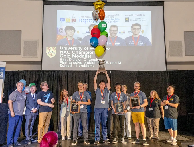 In the centre of the photo: Ramazan Rakhmatullin (master’s student studying combinatorics and optimization), Kevin Wan, (fourth-year computer science and combinatorics and optimization student), Andrew Qi Tang (third-year computer science and combinatorics and optimization student), and team coach Professor Troy Vasiga at the 2023 International Collegiate Programming Contest (ICPC) North America Championship (NAC) hosted by University of Central Florida. 

Photo credit: Michael Roytek