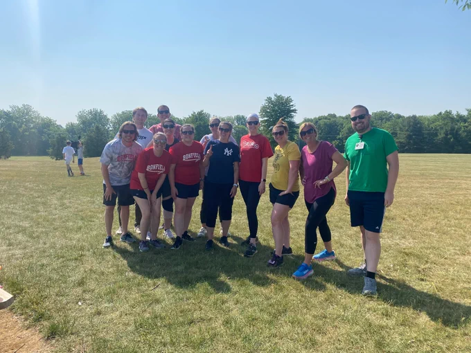 staff members pose for a picture outside in the grass