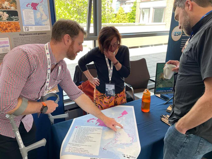 Three people at the JNCC table discussing the UK’s Deep Sea Marine Protected Areas map