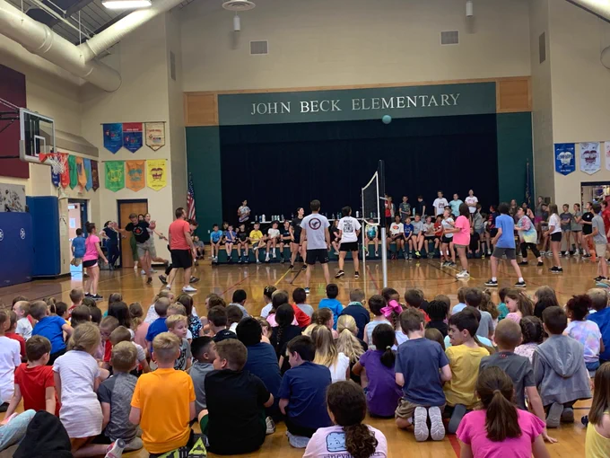 staff vs. student volleyball game inside John Beck Elementary's gym with K-3 grade students watching