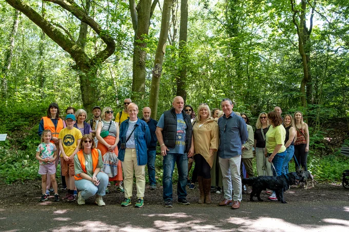A group photo of adults and children smiling in the forest