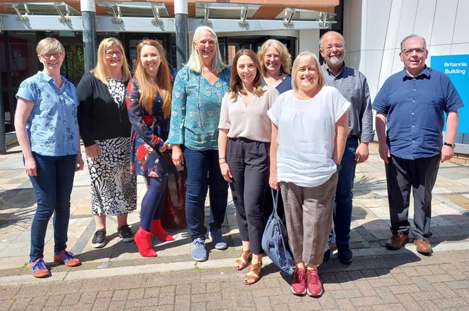 A group of people in smart casual clothes standing outside and smiling