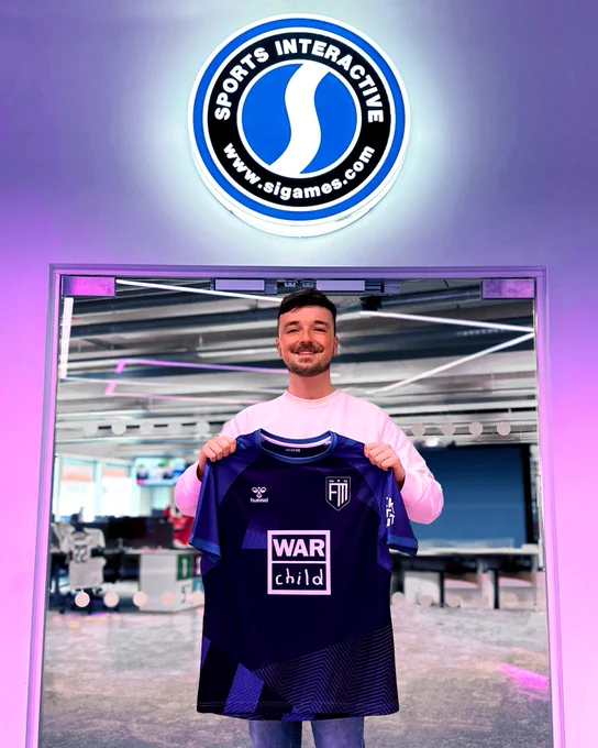 Me holding the 22/23 Football Manager jersey inside the Sports Interactive Studio, London