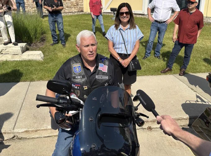 Mike pence on a motorcycle wearing the vest and jeans