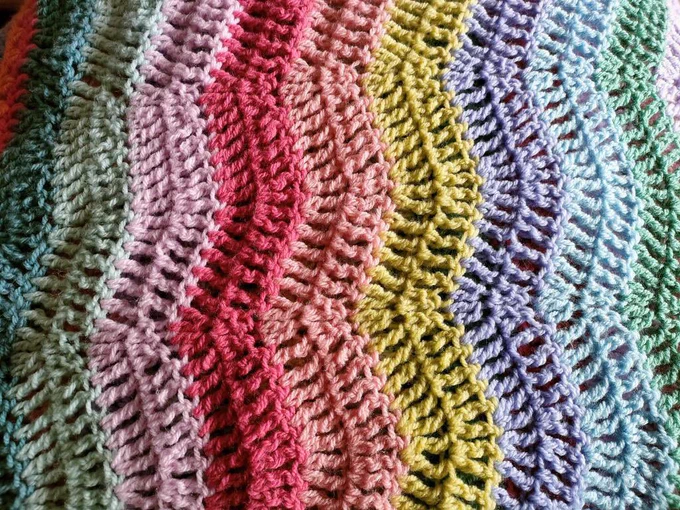 A close up photo of crochet in zigzag rows of varying rainbow colours by artist Ellie Poore