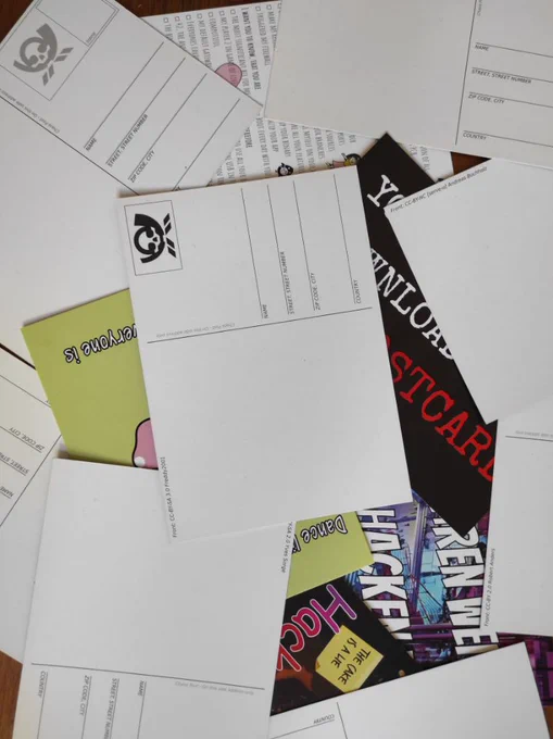 Various postcards laying on a wooden table. Most postcards are back side up so you can't see the motive. The ones that are front side up are mostly covered by the other ones.