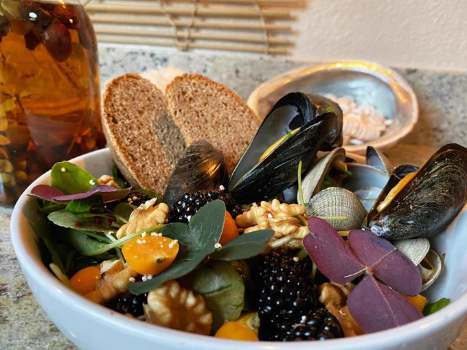 A bowl of muscles with flowers, vegetables, and bread at Cafe Ohlone in Berkeley.
